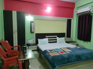 a bedroom with a bed and a desk and a chair at Ditto Room Hotel Kartik, Deoghar in Deoghar