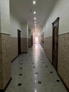 un couloir vide dans un bâtiment doté de portes et de carrelage dans l'établissement ALCAZAR, à Atyraū