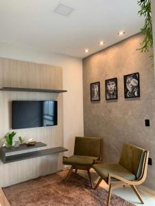 een woonkamer met 2 stoelen en een televisie bij Condomínio tranquilo in Boa Vista