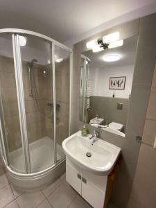 biała łazienka z prysznicem i umywalką w obiekcie La Playa Apartament z ogródkiem w mieście Hel