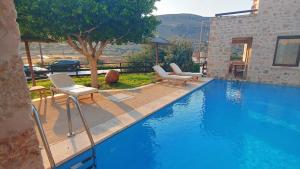 a swimming pool with two lounge chairs next to a house at Simosmare Resort in Elafonisos