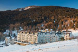 a large building in the snow in front of a mountain at Aparthotel Apartamenty Czarna Góra 109 in Sienna