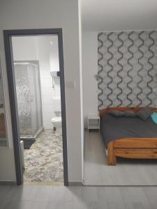 - une chambre avec un lit et une porte menant à une salle de bains dans l'établissement Kiss-Szőllősi Vendégház II LOLA, à Debrecen