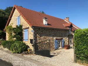 ein Steinhaus mit rotem Dach in der Unterkunft Les Landes in Saint-Pardoux-Corbier