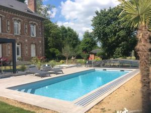 a swimming pool in a yard next to a building at L'hostellerie du chateau in Mesnil-Saint-Nicaise
