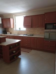 a kitchen with red wooden cabinets and a window at Casa Andrei in Haţeg