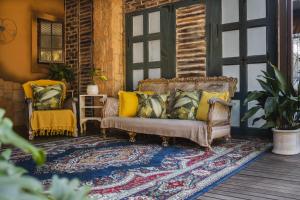 a porch with a couch and two chairs on a rug at La Casa Nostra Rose Garden in Hillcrest