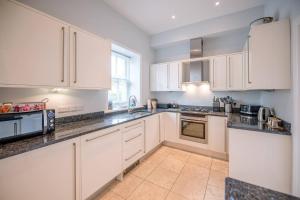 a white kitchen with white cabinets and appliances at Sunset House Blythburgh Air Manage Suffolk in Halesworth