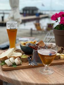 una mesa con una bandeja de comida y dos vasos de cerveza en Boutique Sneekermeer, en Offingawier
