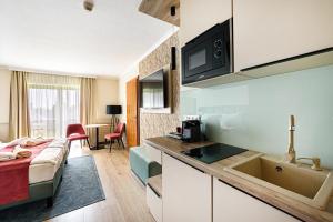 a room with a bed and a kitchen with a sink at Holiday Club Apartman Hotel in Hévíz