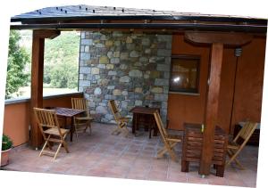un patio con mesas y sillas y una pared de piedra. en Casa Ferro, en Plan