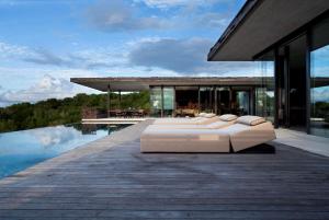 a house with four white beds on a wooden deck at Alila Villas Uluwatu in Uluwatu