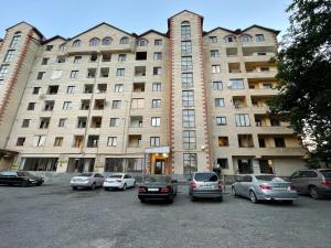 a large building with cars parked in a parking lot at Tsaghkazdor luxury apartment in Tsaghkadzor