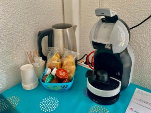 a coffee maker and a basket of food on a table at Hotel Oasis in Argel&egrave;s-sur-Mer