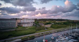 een uitzicht op een gebouw en een rivier met boten bij WestCord Hotel Schylge in West-Terschelling