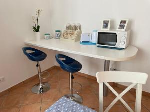 un tavolo bianco con forno a microonde e 2 sgabelli blu di Villa delle Magnolie Montesilvano Abruzzo a Montesilvano