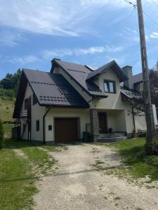 une maison avec un toit noir et une allée dans l'établissement Maciejówka, à Grywałd