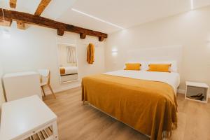 1 dormitorio con 1 cama grande con sábanas de color naranja en Apartamentos BURGOSUITES, en Burgos