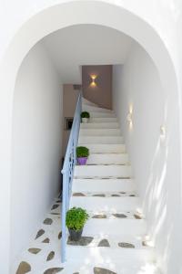 a staircase in a house with a blue railing and potted plants at Lakki Village in Aegiali