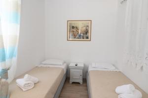 two beds in a white room with towels on them at Lakki Village in Aegiali