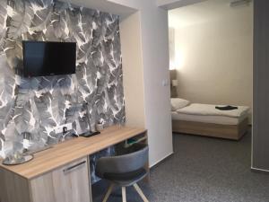 a room with a desk with a television and a bed at Hotel Trim in Pardubice