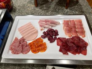 a white plate with meats and fruit on a table at Boutique Hotel La Gorge in Saas-Fee