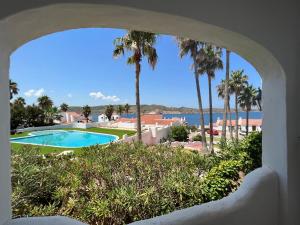 a view of a swimming pool and palm trees at Apartamentos El Bergantin Menorca Club in Fornells