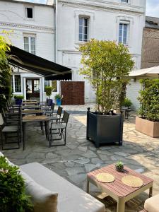 a patio with tables and chairs and a tree at Hôtel Le Patio - Deauville in Deauville