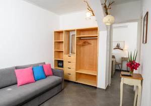a living room with a gray couch with colorful pillows at Lakki Village in Aegiali