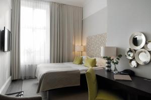 una camera d'albergo con un letto, una scrivania e uno specchio di Elite Grand Hotel Gävle a Gävle