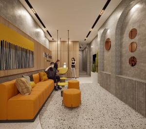 a lobby with a yellow couch and two people standing at The Hotel Nicecy in Ho Chi Minh City