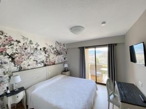 - une chambre avec un grand lit blanc et une fenêtre dans l'établissement Hôtel Le Colombier, à Moustiers-Sainte-Marie