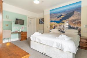 - une chambre avec un grand lit blanc orné d'une peinture murale dans l'établissement Padarn Hotel, à Llanberis