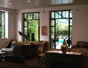 sala de estar con sofá, mesas y ventanas en Fawlty Towers Accommodation & Activities, en Livingstone