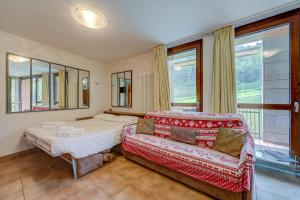 a bedroom with a bed and a couch and windows at La Marmotta Campo Smith on the Ski Slopes - Happy Rentals in Bardonecchia