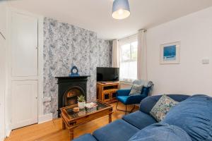 a living room with a blue couch and a fireplace at Magdala Cottage -village Location- Dog Friendly in Kent
