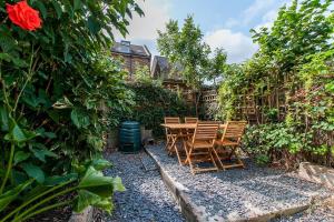 a patio with chairs and a table in a garden at Magdala Cottage -village Location- Dog Friendly in Kent