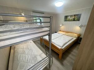 2 Etagenbetten in einem kleinen Zimmer mit einem weiteren Bett in der Unterkunft Strandhussiedlung Rügen in Dranske