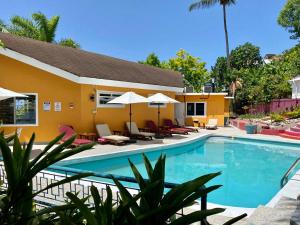 einen Pool in einem Hotel mit Stühlen und Sonnenschirmen in der Unterkunft The Blue Orchid B&B in Montego Bay