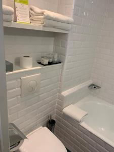een witte badkamer met een toilet en een bad bij Hôtel Eiffel XV in Parijs