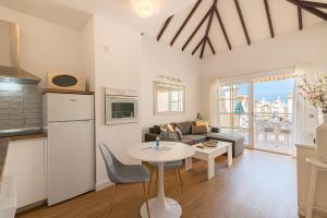 eine Küche und ein Wohnzimmer mit einem Tisch und einem Sofa in der Unterkunft SUNSHINE HOLIDAYS HOME , Playa de Fañabe in Adeje
