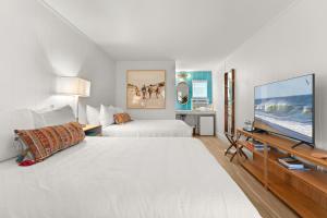 a hotel room with two beds and a flat screen tv at Surf Shanty Motel in Dewey Beach