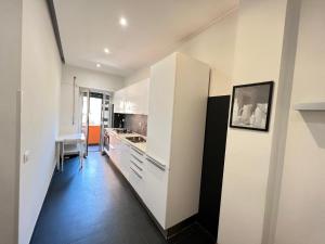 cocina con armarios blancos y suelo negro en JS appartament Luxury, en Roma