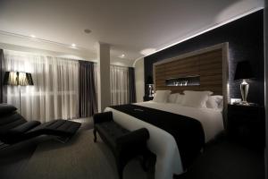 サンティアゴ・デ・コンポステーラにあるキャピトル ブティック ホテルの大きなベッドと椅子が備わるホテルルームです。