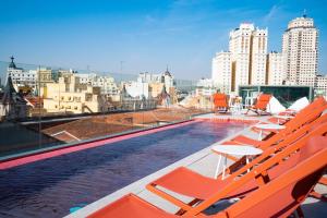 a swimming pool on the roof of a building with orange chairs at Akeah Hotel Gran Vía in Madrid