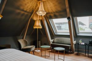 a bedroom with a bed and a couch and two chairs at In de Brouwerij in Leeuwarden