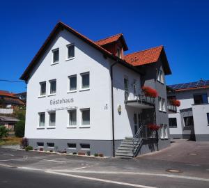 een wit gebouw met een rood dak bij Landgasthof Zum Stern in Hammelburg- Obererthal