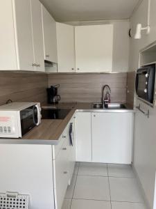 a kitchen with white cabinets and a microwave and a sink at Vue mer et verdure in Villers-sur-Mer +22 photos