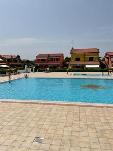 uma grande piscina azul com edifícios ao fundo em Villaggio dei Fiori Apart- Hotel 4 Stars - Family Resort-Petz Friendly-With Hypermarket-Delivery Restaurant-Pizzeria-With Breakfast Room with Supplement em Caorle