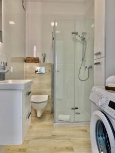 a bathroom with a shower and a toilet and a washing machine at REMAR - Apartments Lake Biale in Augustów